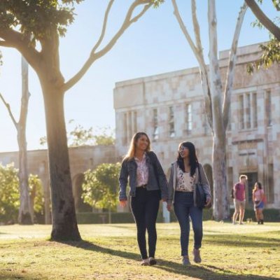 Two people walking across the lawn at a university